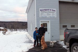 Kolby & Mike Rossignol with the family pooches Buddy and Gizmo  in front of the Aroostook Shop & Garage