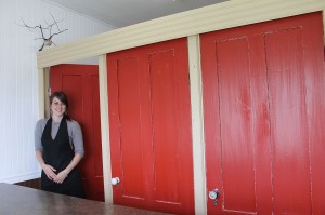 Erica Kent is standing in front of the beautiful red door wall in her salon