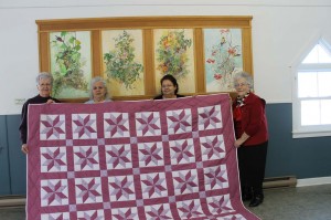 Beatrice Lockhart, Marlene Christophersen, Dorothy Pelkey and Carolyn Goodine display the finished quilt they began in January