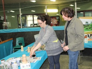 Emily shows Stacey how to make your own biodegradable seedling pots from rolled up newspaper wrapped around a wine bottle